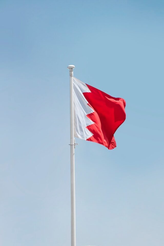 The flag of Bahrain flying against a clear sky